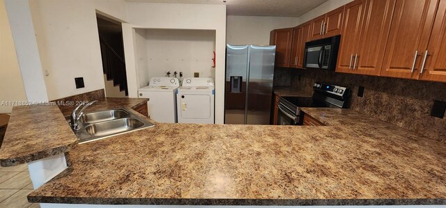 kitchen featuring appliances with stainless steel finishes, sink, washer and clothes dryer, and kitchen peninsula