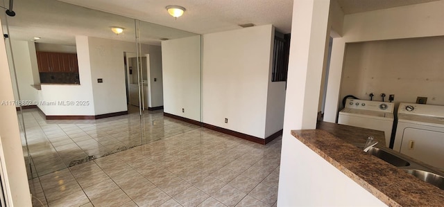 unfurnished room featuring sink, a textured ceiling, and washer and clothes dryer