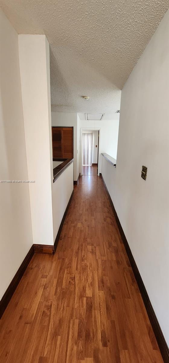 corridor with hardwood / wood-style floors and a textured ceiling