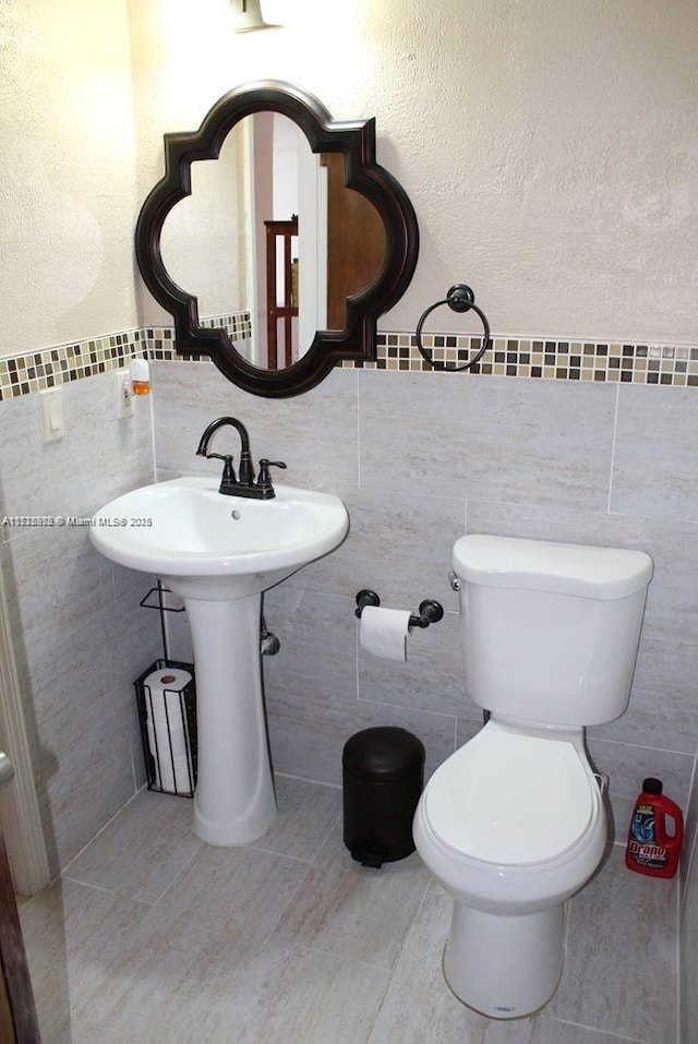 bathroom with tile patterned flooring, tile walls, and toilet