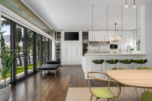 kitchen featuring decorative light fixtures, white cabinetry, dark hardwood / wood-style flooring, and built in appliances