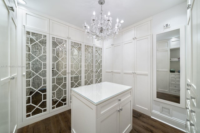 walk in closet with dark wood-type flooring and an inviting chandelier