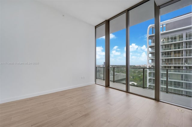 spare room with expansive windows and light wood-type flooring