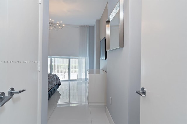 corridor with light tile patterned floors and a notable chandelier