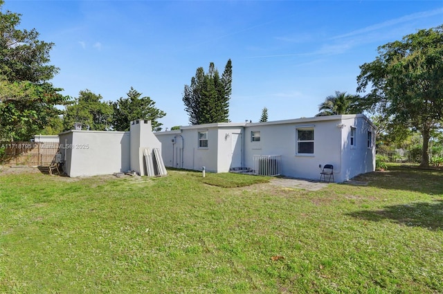 rear view of property featuring a yard and central AC