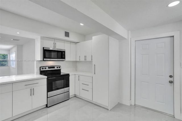 kitchen featuring white cabinets, appliances with stainless steel finishes, and backsplash