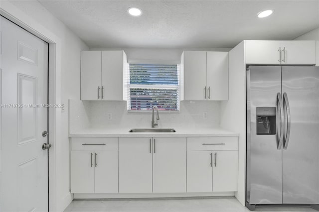 kitchen featuring backsplash, white cabinets, sink, a textured ceiling, and stainless steel fridge with ice dispenser