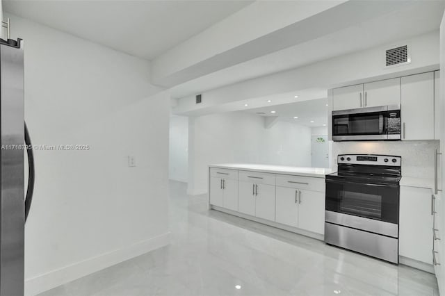 kitchen featuring decorative backsplash, appliances with stainless steel finishes, and white cabinetry