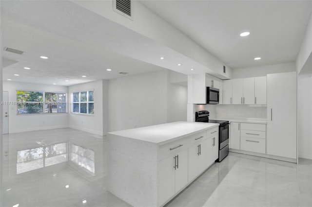 kitchen with tasteful backsplash, kitchen peninsula, white cabinets, and appliances with stainless steel finishes