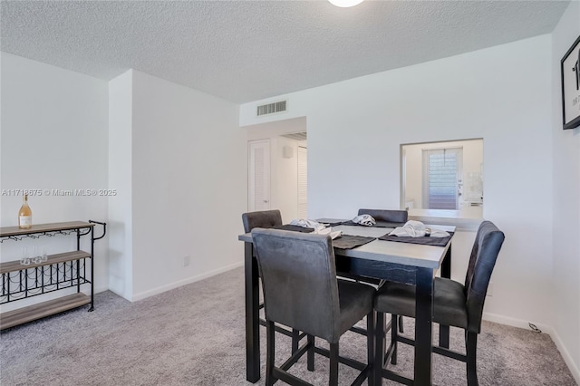 carpeted dining space with a textured ceiling