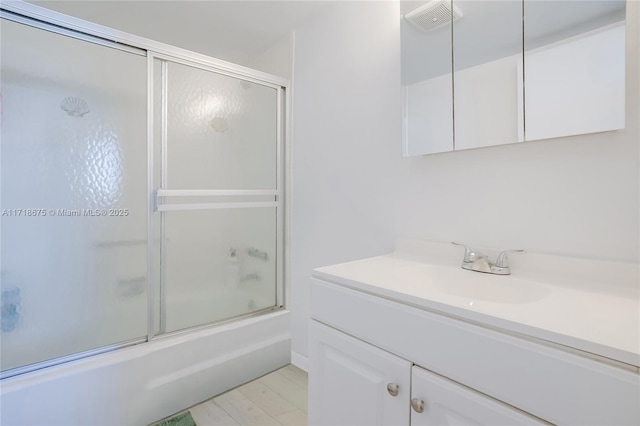 bathroom featuring combined bath / shower with glass door, hardwood / wood-style floors, and vanity