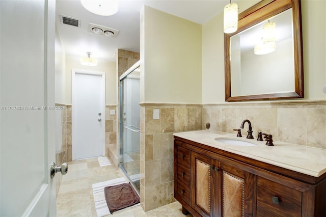 bathroom with tile patterned floors, vanity, a shower with shower door, and tile walls