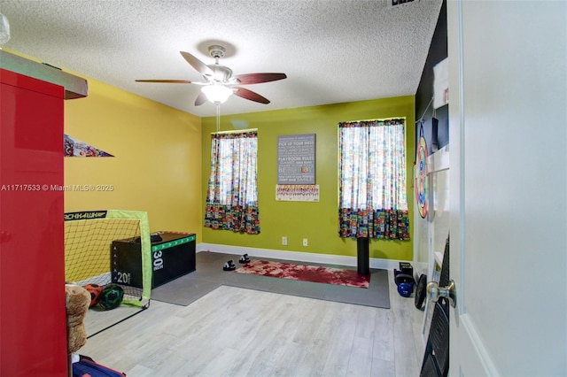 rec room featuring ceiling fan, light hardwood / wood-style floors, and a textured ceiling