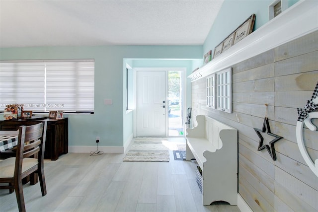 foyer entrance featuring a textured ceiling and wooden walls