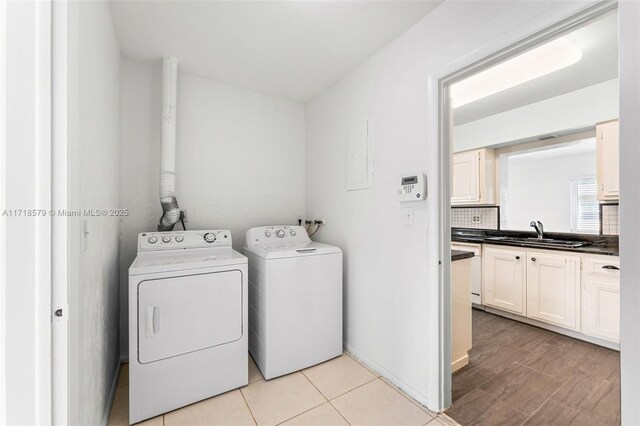 laundry room featuring light tile patterned flooring, sink, and washing machine and dryer