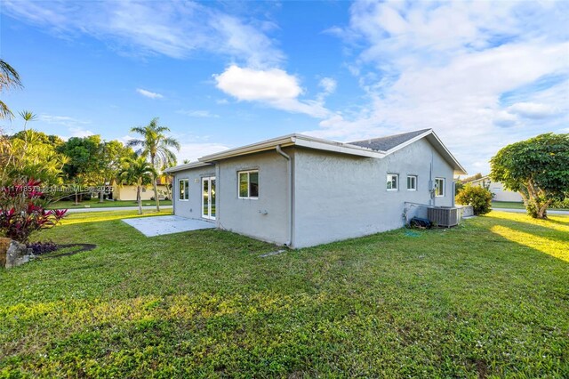 view of side of property with a yard and central air condition unit