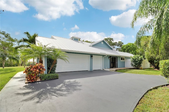 view of front of house with a front lawn, an attached garage, driveway, and metal roof