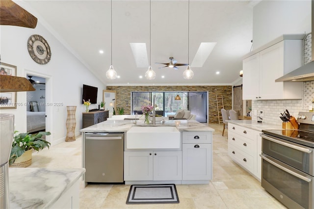 kitchen with a sink, stainless steel appliances, light stone countertops, and a skylight