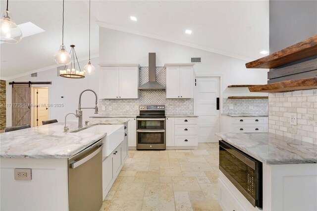 kitchen with open shelves, a sink, stainless steel appliances, a barn door, and wall chimney range hood