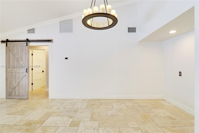 spare room featuring a barn door, baseboards, visible vents, and stone tile flooring