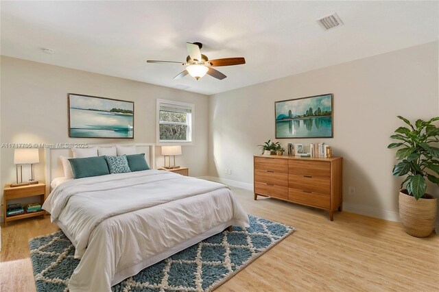 bedroom with light wood-type flooring, visible vents, baseboards, and ceiling fan