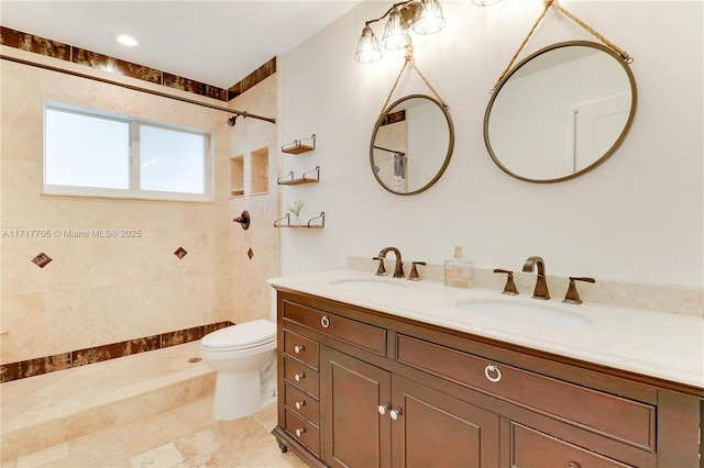 full bath with a tile shower, double vanity, toilet, and a sink