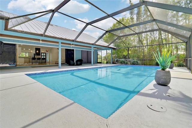 outdoor pool featuring glass enclosure and a patio