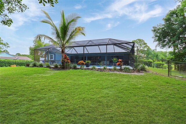 rear view of house with glass enclosure, a fenced in pool, a fenced backyard, and a lawn