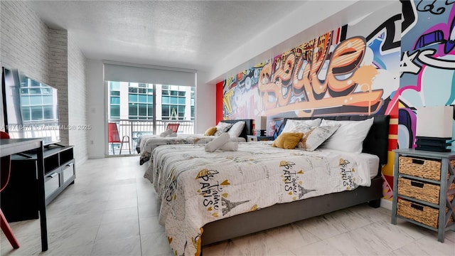 bedroom featuring a textured ceiling, access to outside, and brick wall