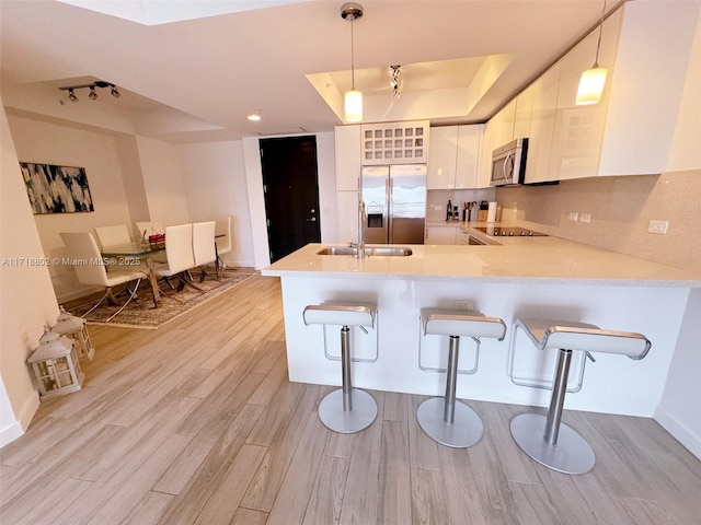 kitchen with kitchen peninsula, a breakfast bar, hanging light fixtures, and appliances with stainless steel finishes