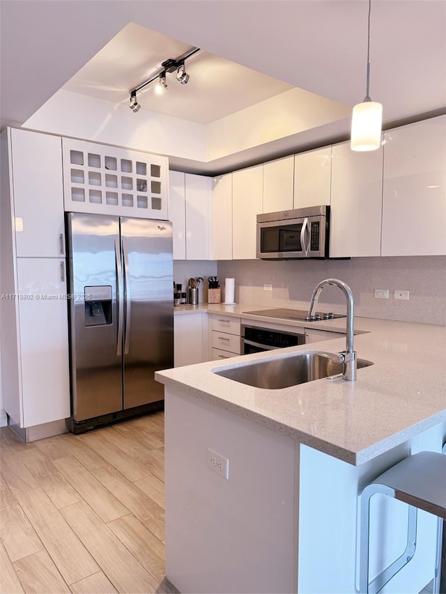 kitchen with hanging light fixtures, light hardwood / wood-style flooring, white cabinetry, kitchen peninsula, and stainless steel appliances