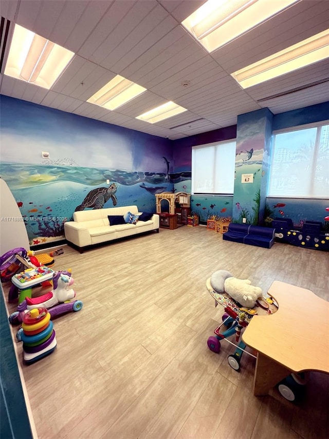 playroom featuring a paneled ceiling and hardwood / wood-style flooring