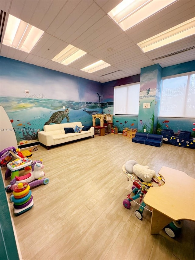 rec room with a paneled ceiling and hardwood / wood-style flooring