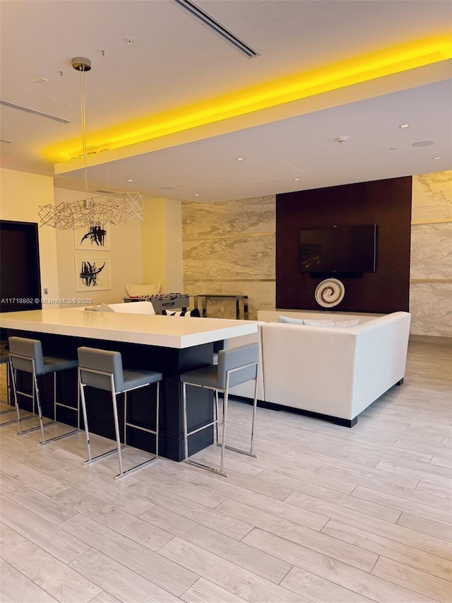 kitchen with a breakfast bar, light hardwood / wood-style floors, a spacious island, and hanging light fixtures