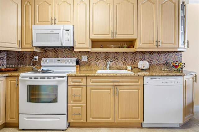 kitchen with decorative backsplash, white appliances, light stone counters, and sink