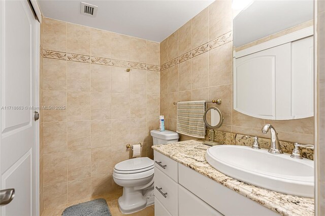 bathroom with vanity, toilet, and tile walls