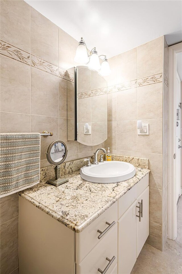 bathroom featuring vanity and tile walls