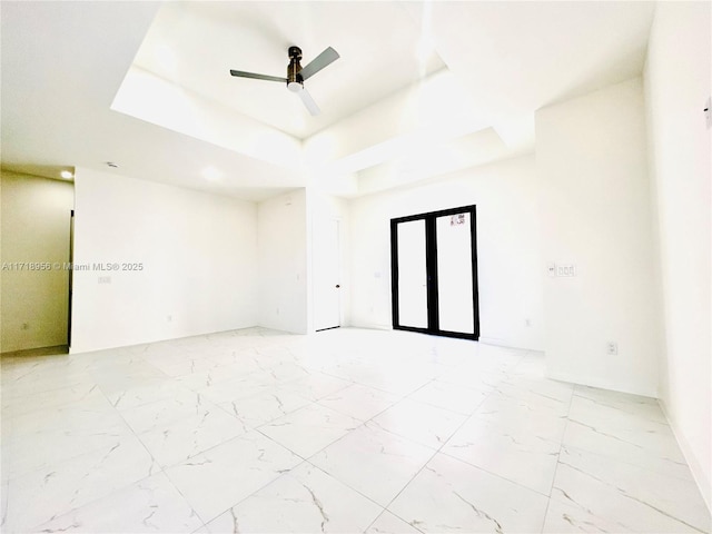 empty room featuring a tray ceiling and ceiling fan