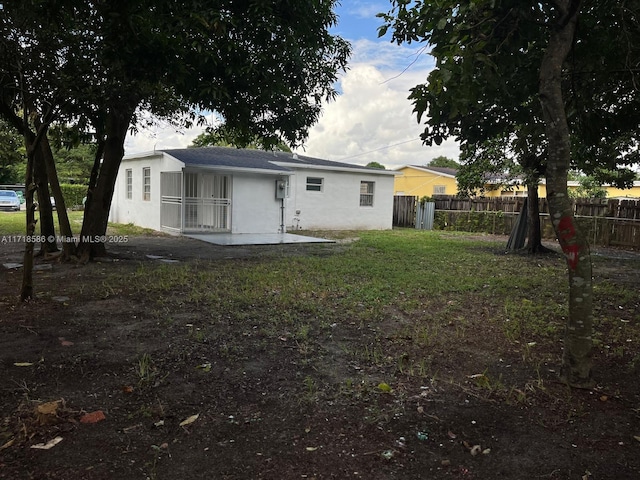 back of house with a lawn and a patio