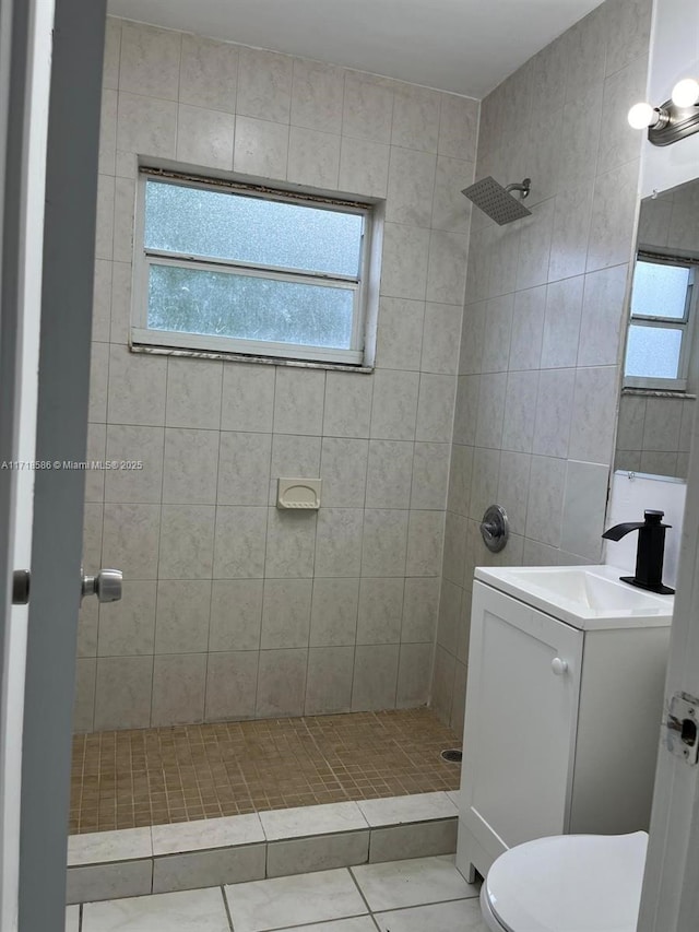 bathroom featuring tile patterned floors, vanity, toilet, and a tile shower