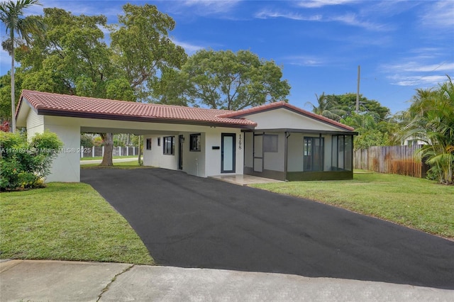 view of front of house with a carport, a sunroom, and a front yard