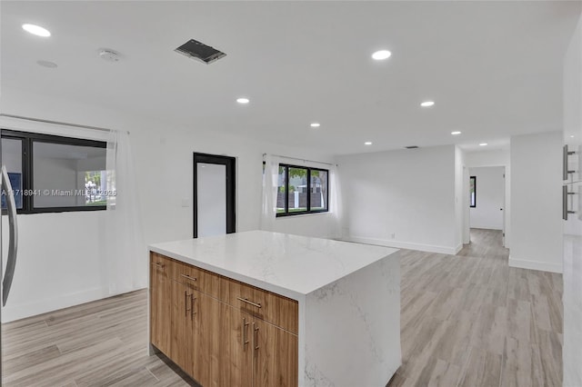 kitchen with light stone countertops, light hardwood / wood-style floors, and a kitchen island