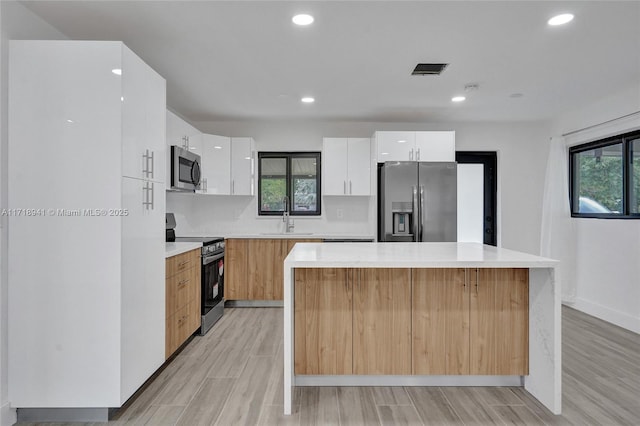 kitchen with sink, white cabinetry, stainless steel appliances, a center island, and decorative backsplash