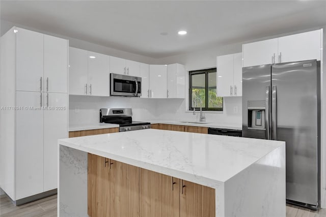 kitchen with appliances with stainless steel finishes, a center island, sink, and white cabinets