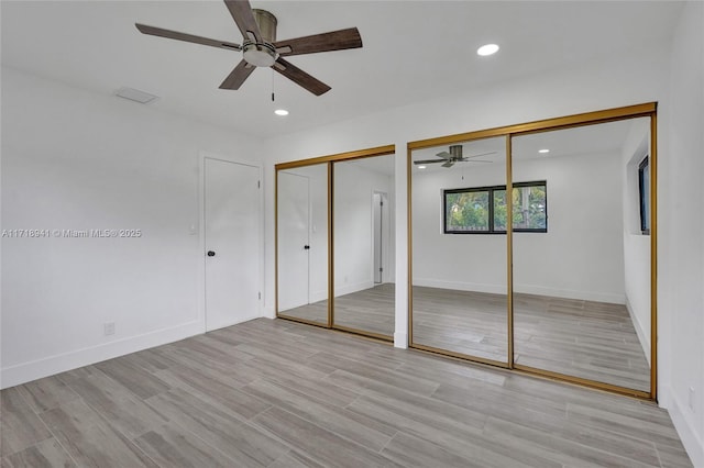 unfurnished bedroom featuring multiple closets, ceiling fan, and light hardwood / wood-style floors