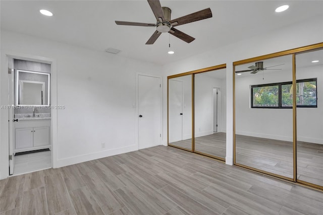 unfurnished bedroom with multiple closets, ceiling fan, connected bathroom, and light hardwood / wood-style floors