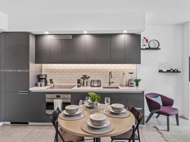 kitchen featuring tasteful backsplash, black electric cooktop, stainless steel oven, and sink