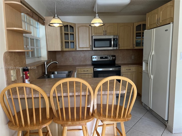 kitchen featuring appliances with stainless steel finishes, a kitchen breakfast bar, sink, light brown cabinets, and light tile patterned flooring