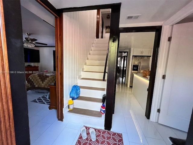 stairs featuring tile patterned floors and ceiling fan