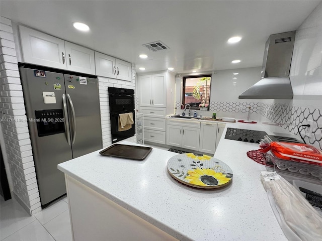 kitchen featuring white cabinets, stainless steel fridge with ice dispenser, black double oven, and wall chimney range hood